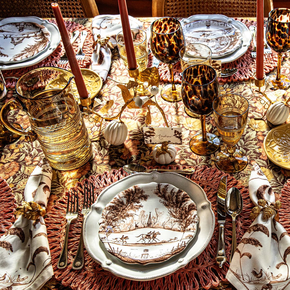 Elegant Thanksgiving table setting with patterned plates, glasses, and place cards.