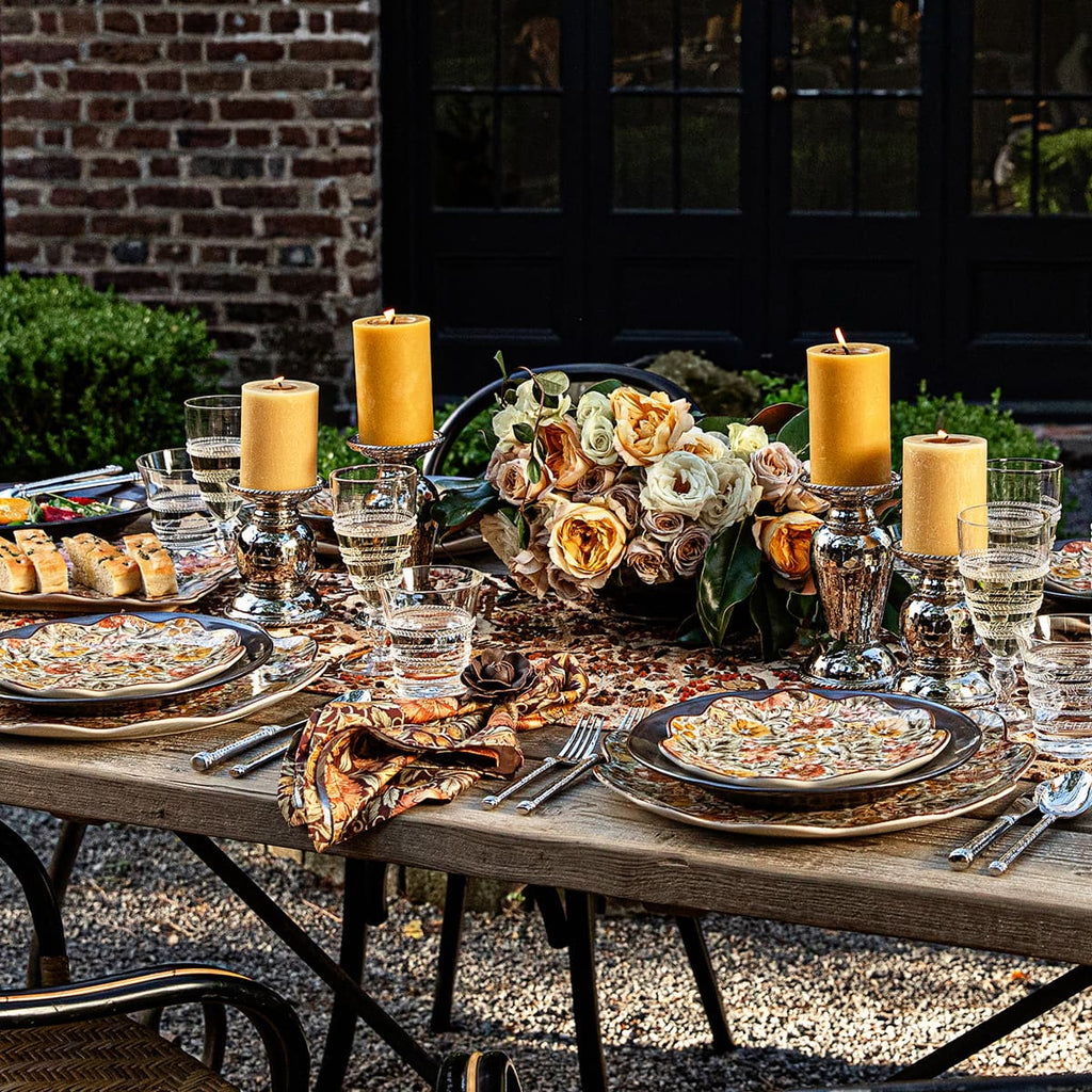 Outdoor tablescape with floral plates, Amalia glasses, Graham candles, and floral arrangements. 