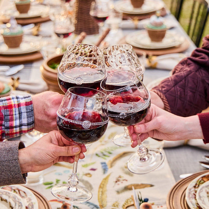 People toasting with red wine glasses at a festive table setting.