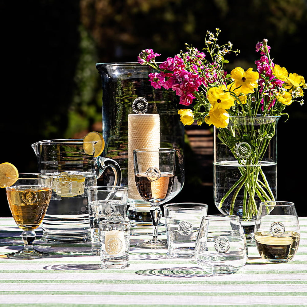 Variety of Berry & Thread glassware displayed outside on a green stripe tablecloth