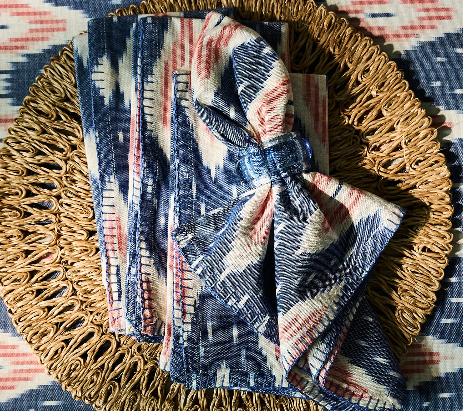 Set of patterned napkins on a woven placemat with a colorful background