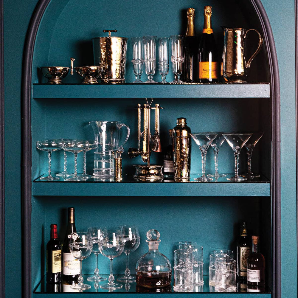 Bar cabinet full of Bohemian glassware and metal barware. 