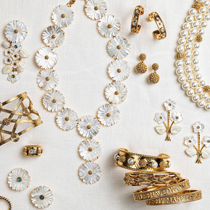 Gold and White Capucine De Wulf jewelry on a white cloth.