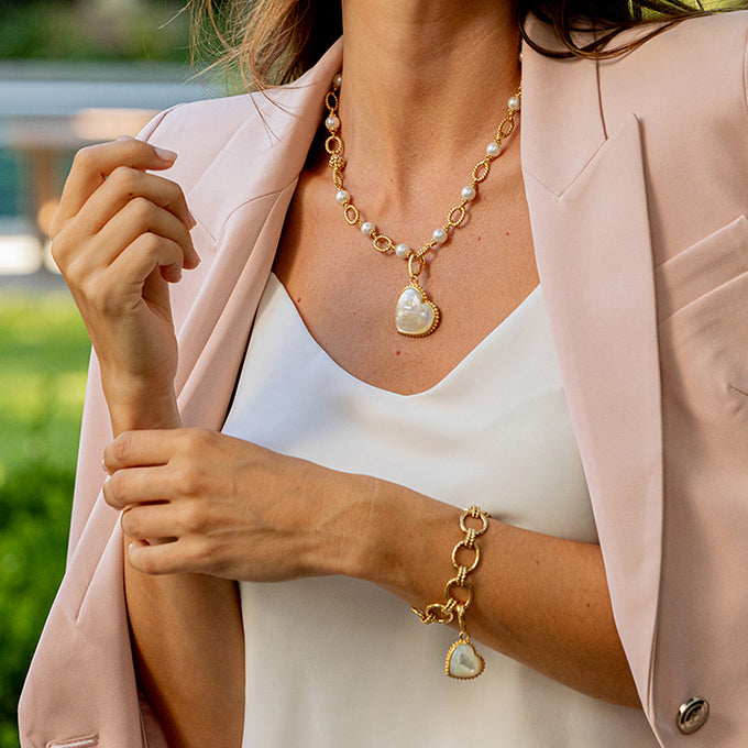 Woman wearing a pearl necklace and bracelet with a blurred outdoor background
