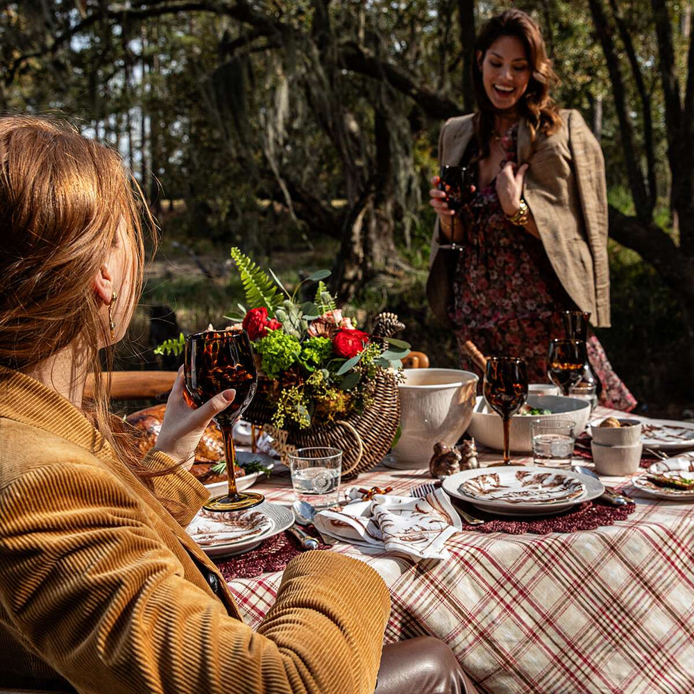 Women gathering at a table enjoying glasses of wine amongst a tablescape