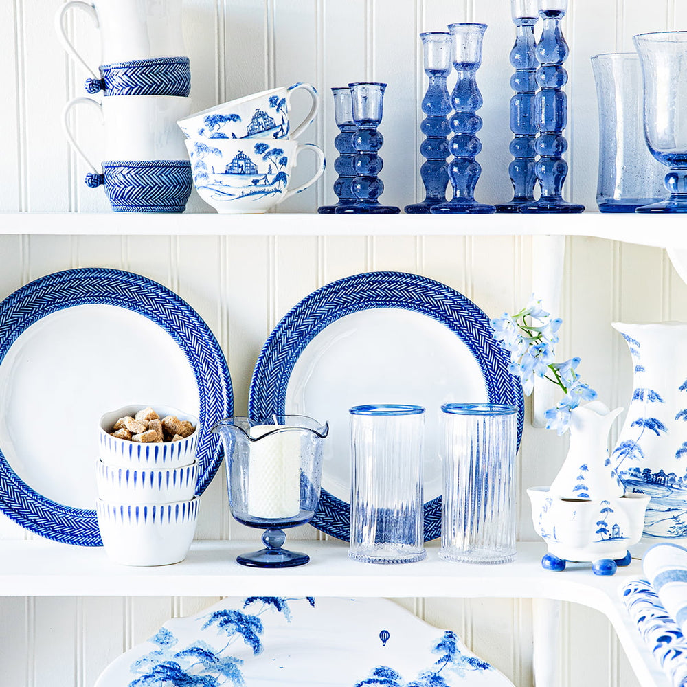 Variety of blue glassware, plates and serveware stacked on a cabinet