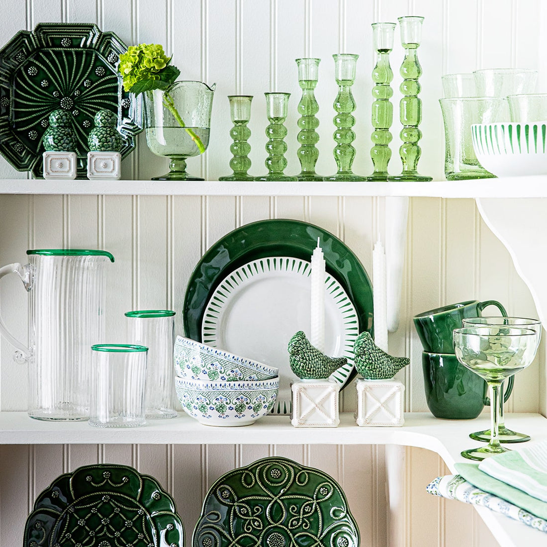 Open shelving pantry showcasing white and green ceramic and glass tableware.