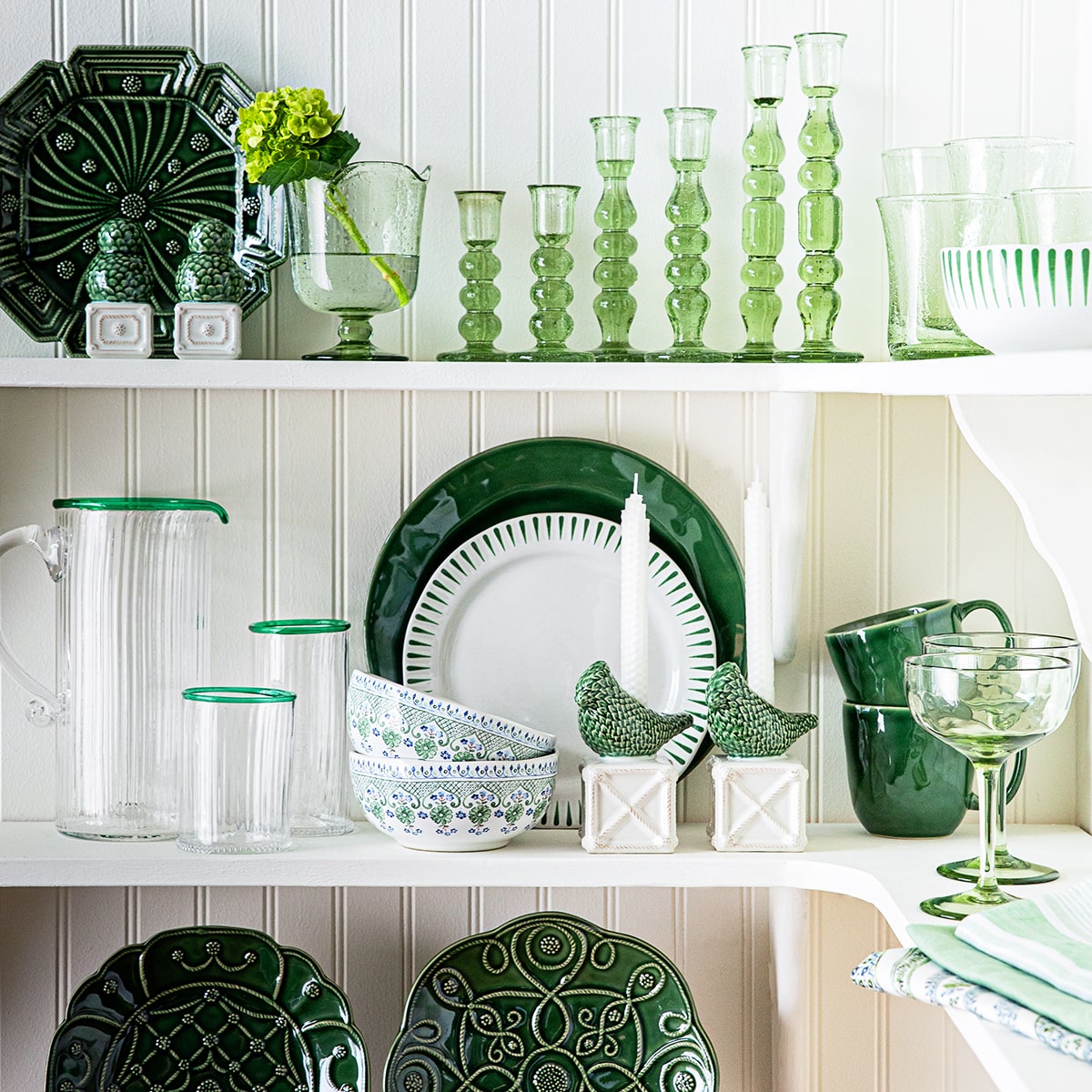 Open shelving pantry showcasing white and green ceramic and glass tableware.