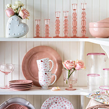 Open shelving pantry showcasing white and pink ceramic and glass tableware.