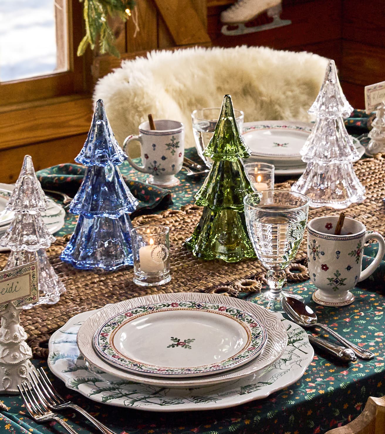 Decorative Christmas table setting with glass trees and patterned plates.