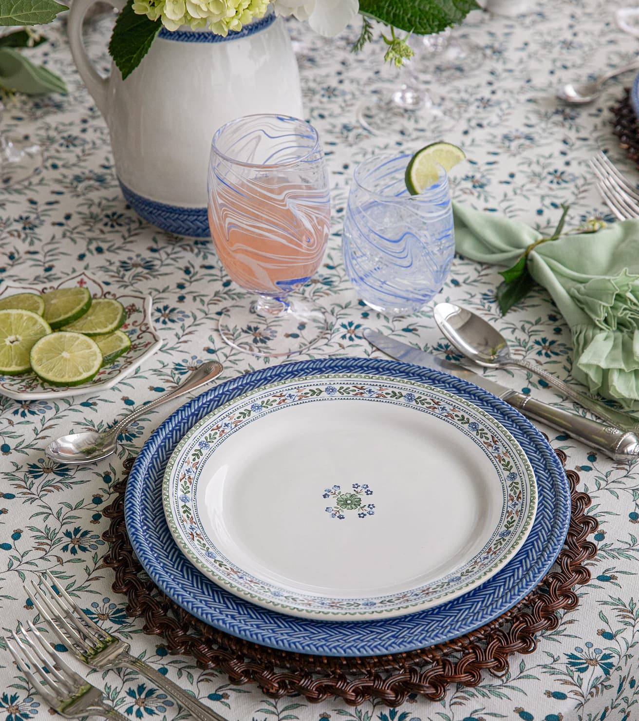 Set table with decorative plates, glasses, and cutlery on a patterned tablecloth.