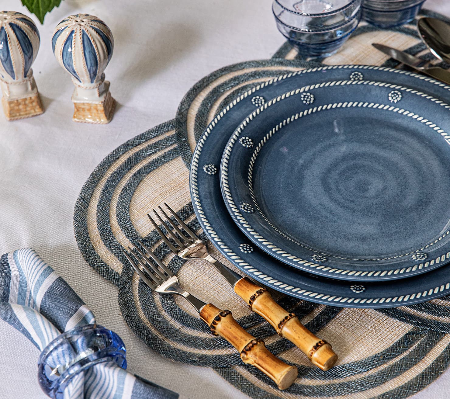 Blue ceramic plates with decorative patterns on a table setting with cutlery and napkins.