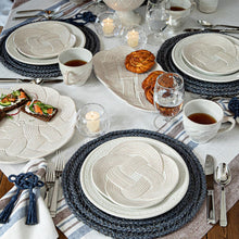 Elegant table setting with woven placemats, croissants, and tea service.