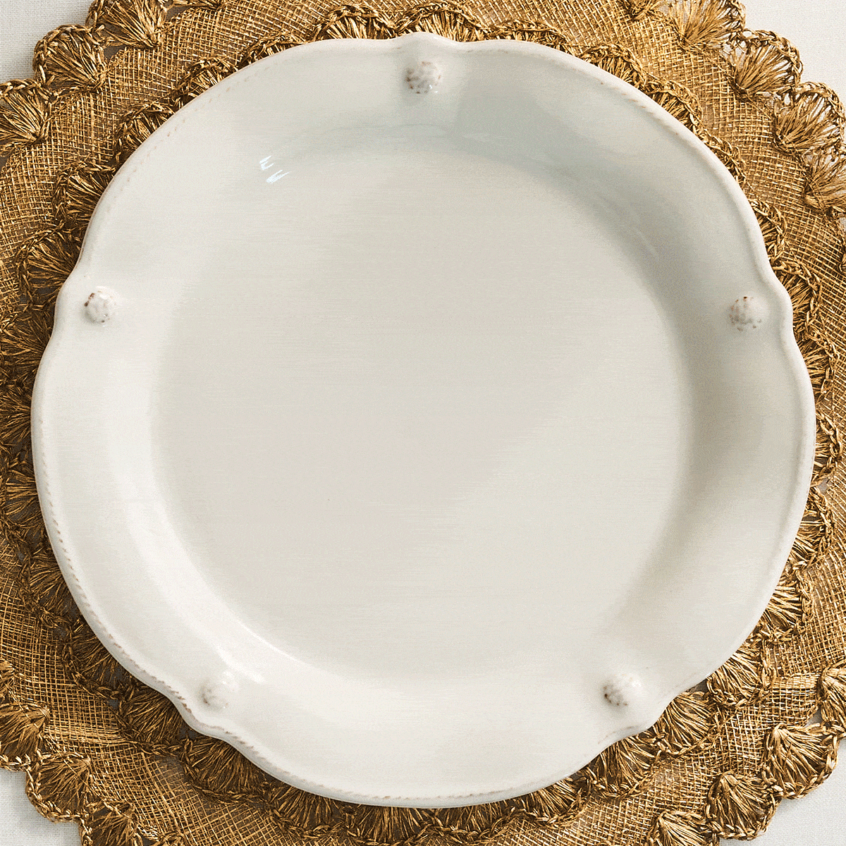 Moveable gif featuring three changing stacked ceramic plates. The plate patterns are scalloped edges and raised floral relief, blue, black and north pole themed on a textured gold placement.