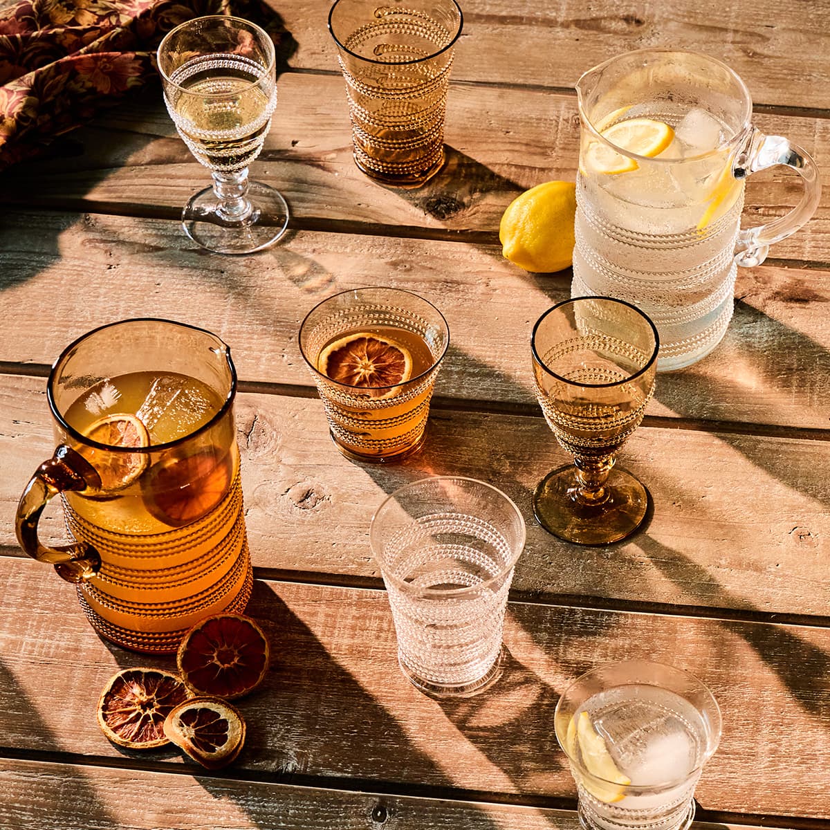 Collection of drinks on a wooden table with glasses, mugs, and a pitcher.