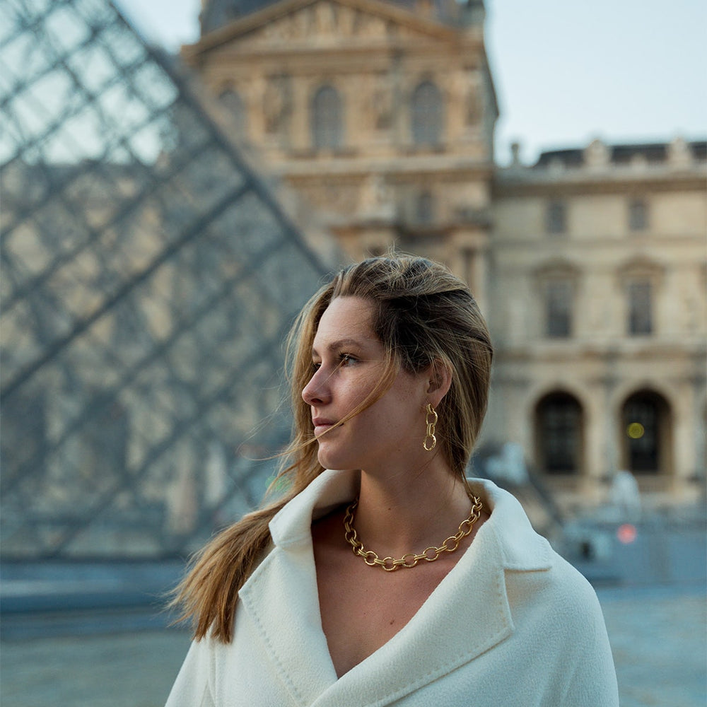 Cleopatra gold earrings dangle from the ears of a Parisian woman.