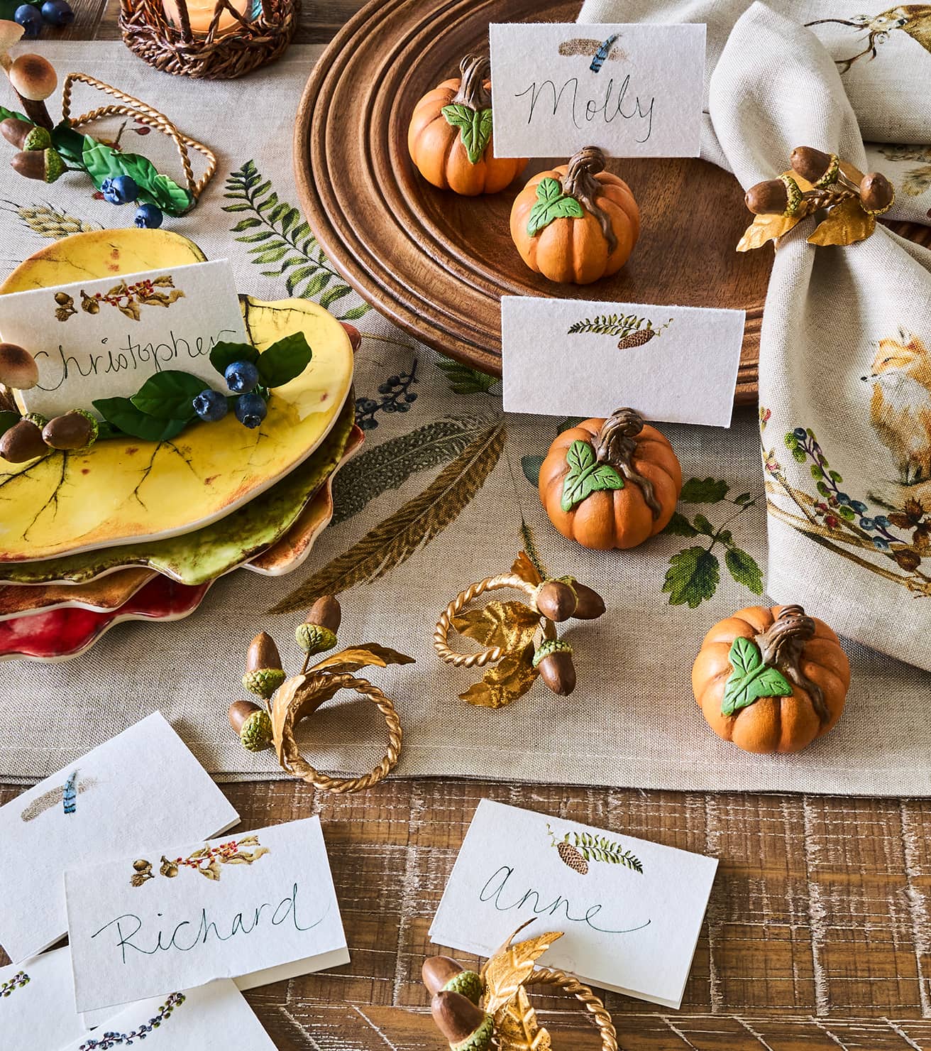 Decorative table setting with pumpkins, name cards, and autumn-themed decor.