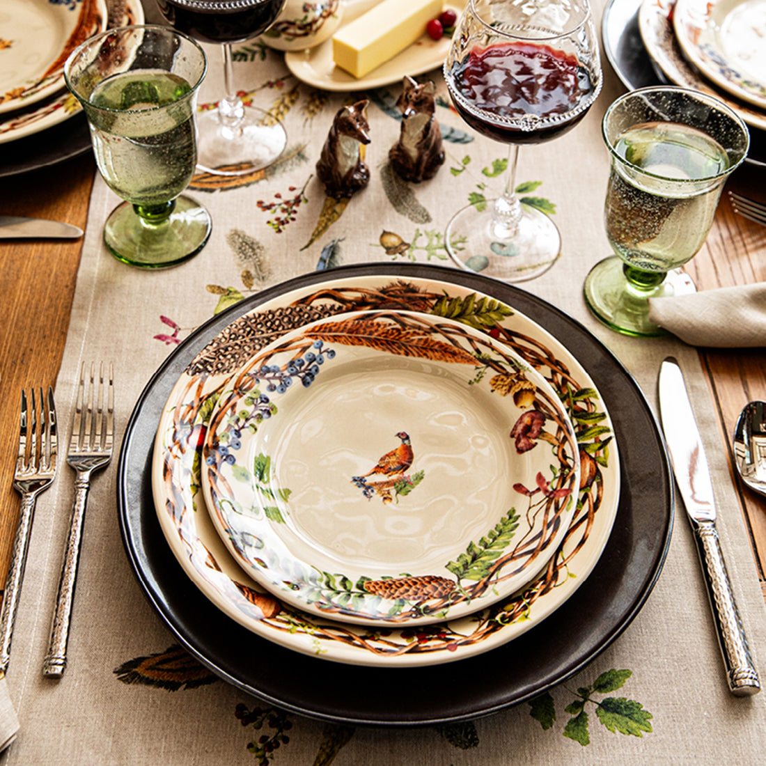 Decorative table setting with floral and animal patterns on plates and glasses.