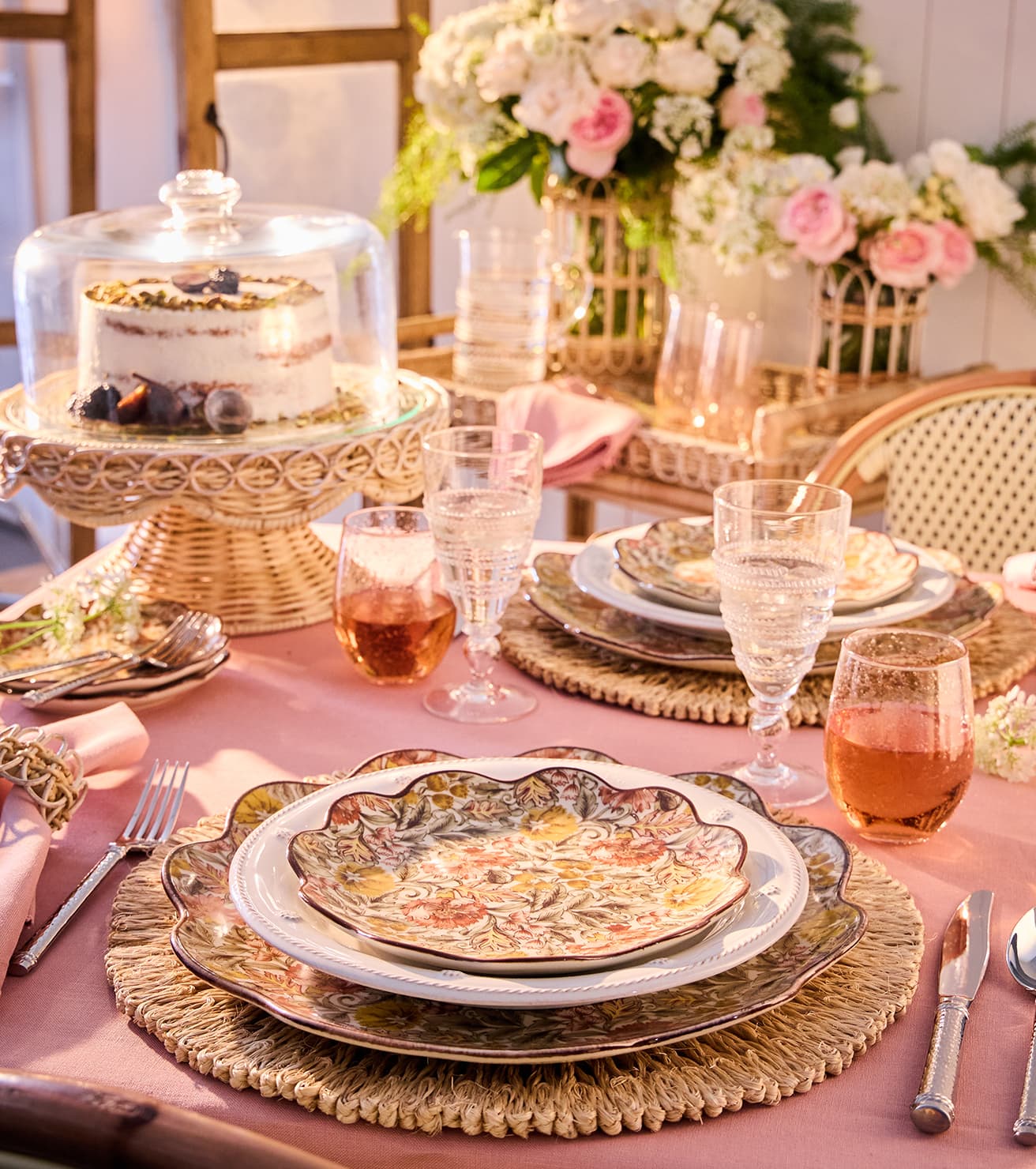 Elegant dining table setting with floral centerpieces, cake, and glassware.