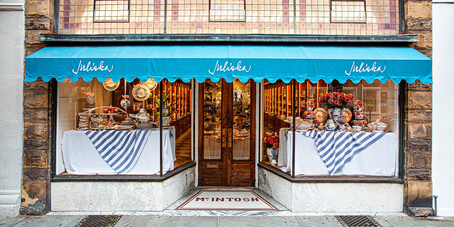 Front view of the Charleston Juliska Store with teal awnings and gorgeous window displays.