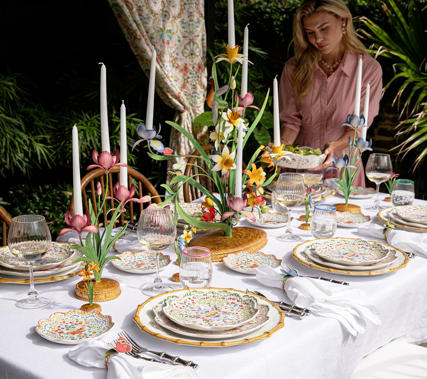 Elegant table setting with floral centerpieces and a woman arranging items.