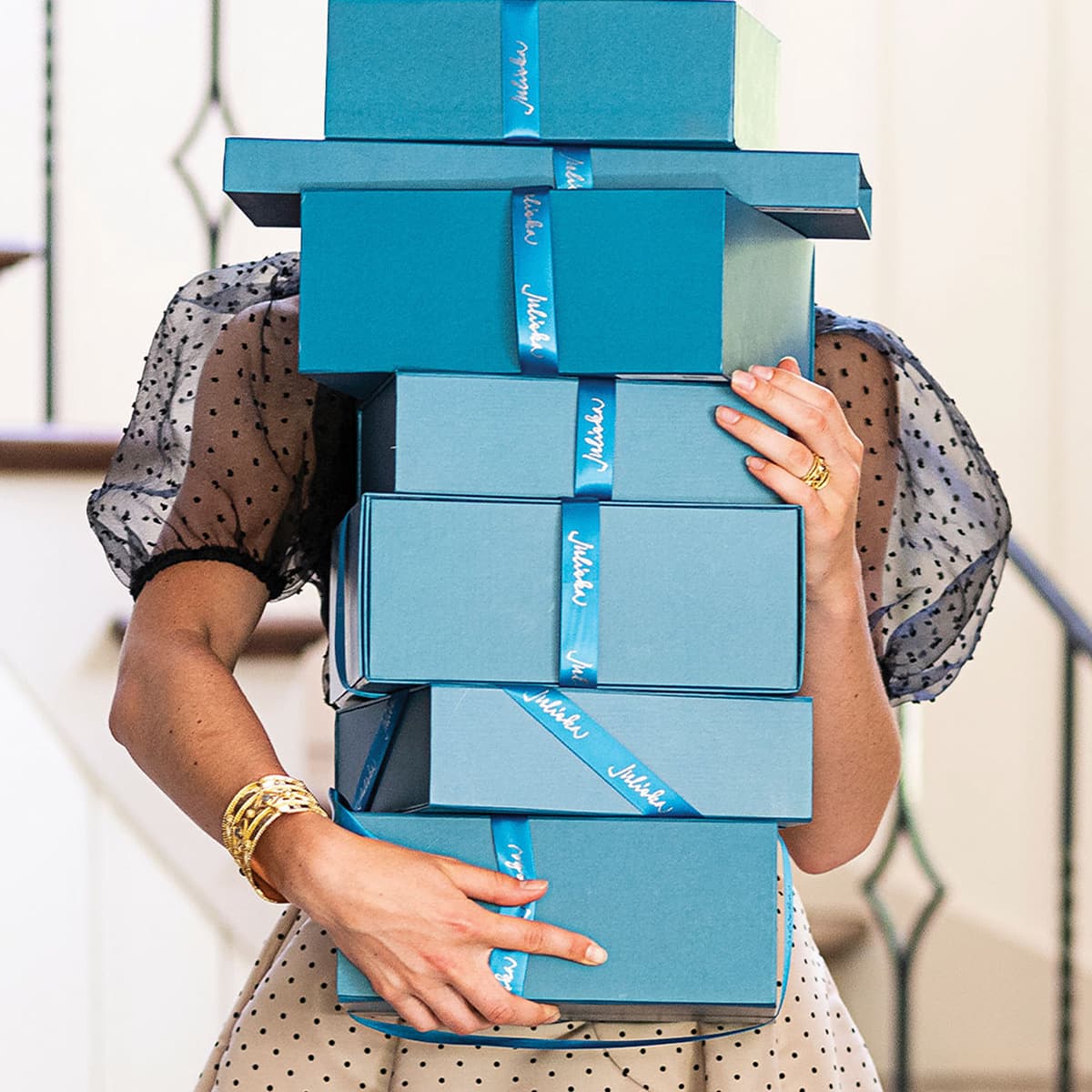 Person holding a stack of blue gift boxes with ribbons