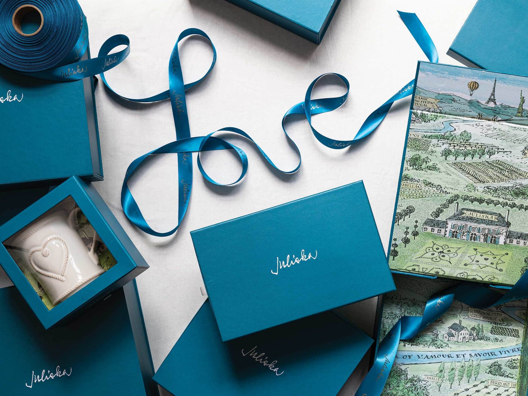 Blue gift boxes with ribbons and a decorative book on a white surface