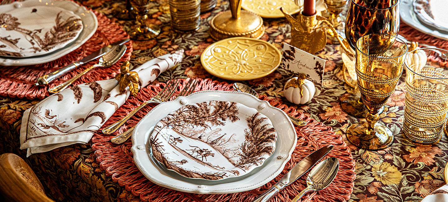 Decorative table setting with plates, cutlery, and glasses on a patterned tablecloth.