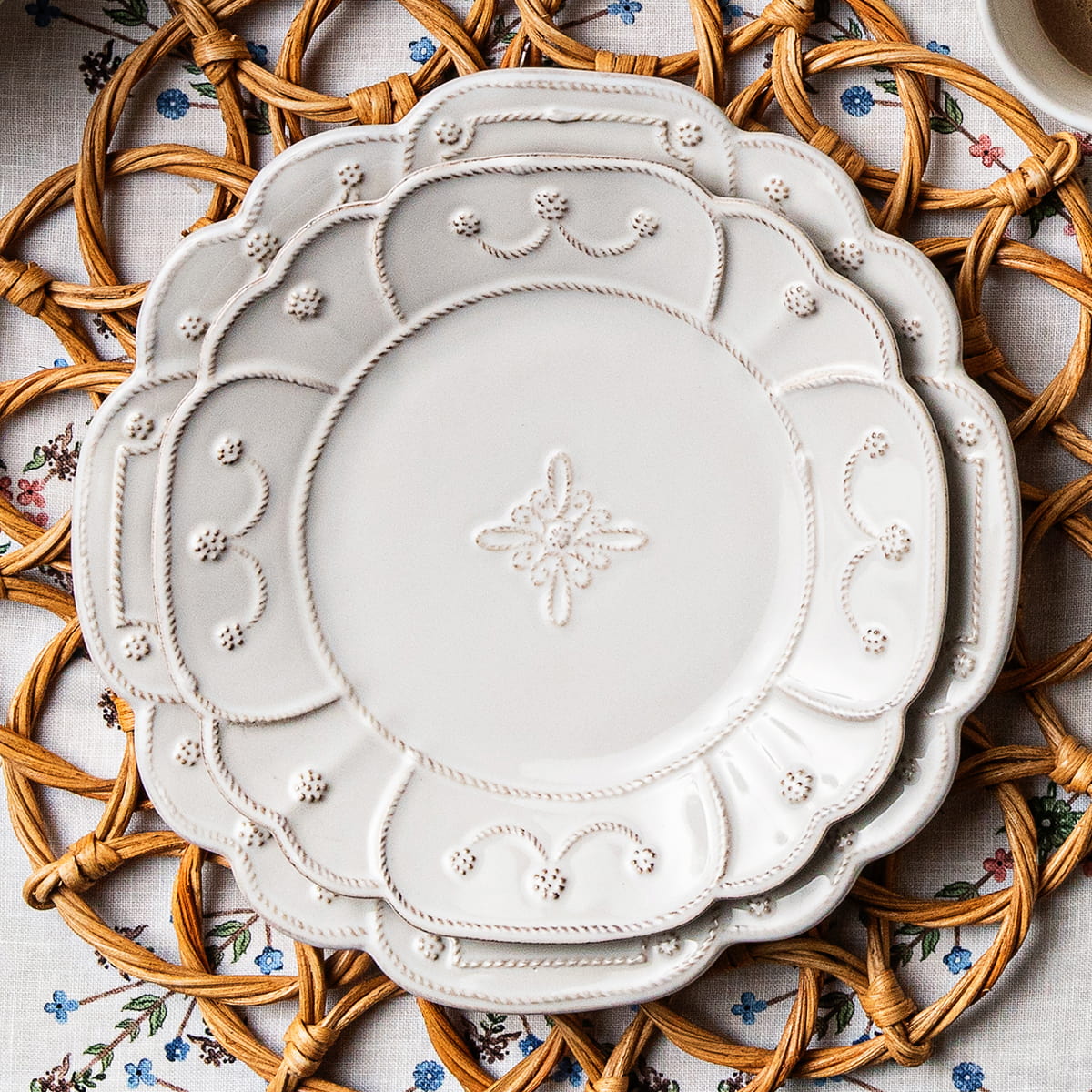 2 Jardin Du Monde whitewash plates on top of a provence rattan placemat and ville seville tablecloth
