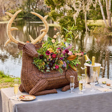 Decorative wicker deer with floral arrangement on a table by a lake