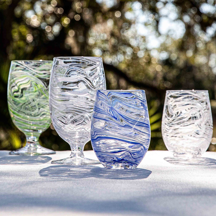 Green, blue and clear puro goblets and stemless glasses on a white tablecloth