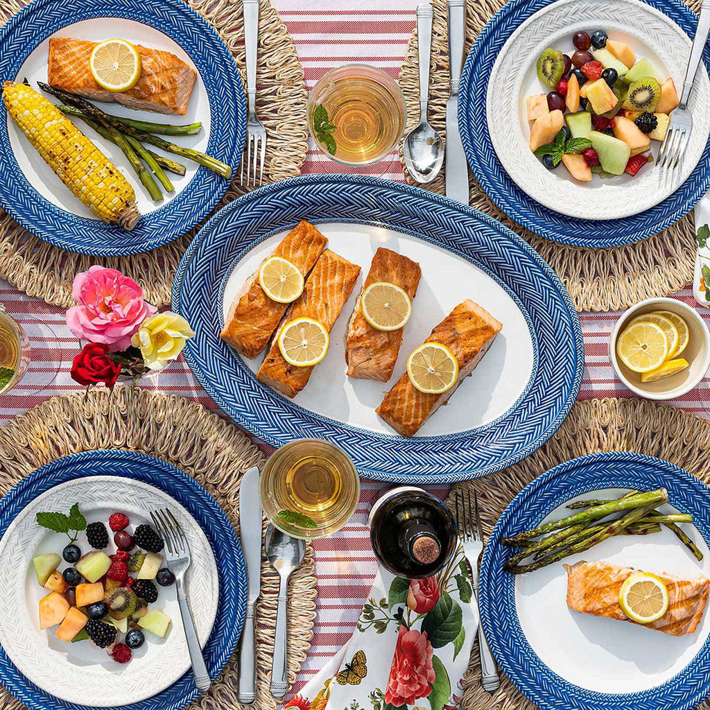 Le Panier Delft Blue and Whitewash plates on straw placemats amongst an outdoor dining table set for four