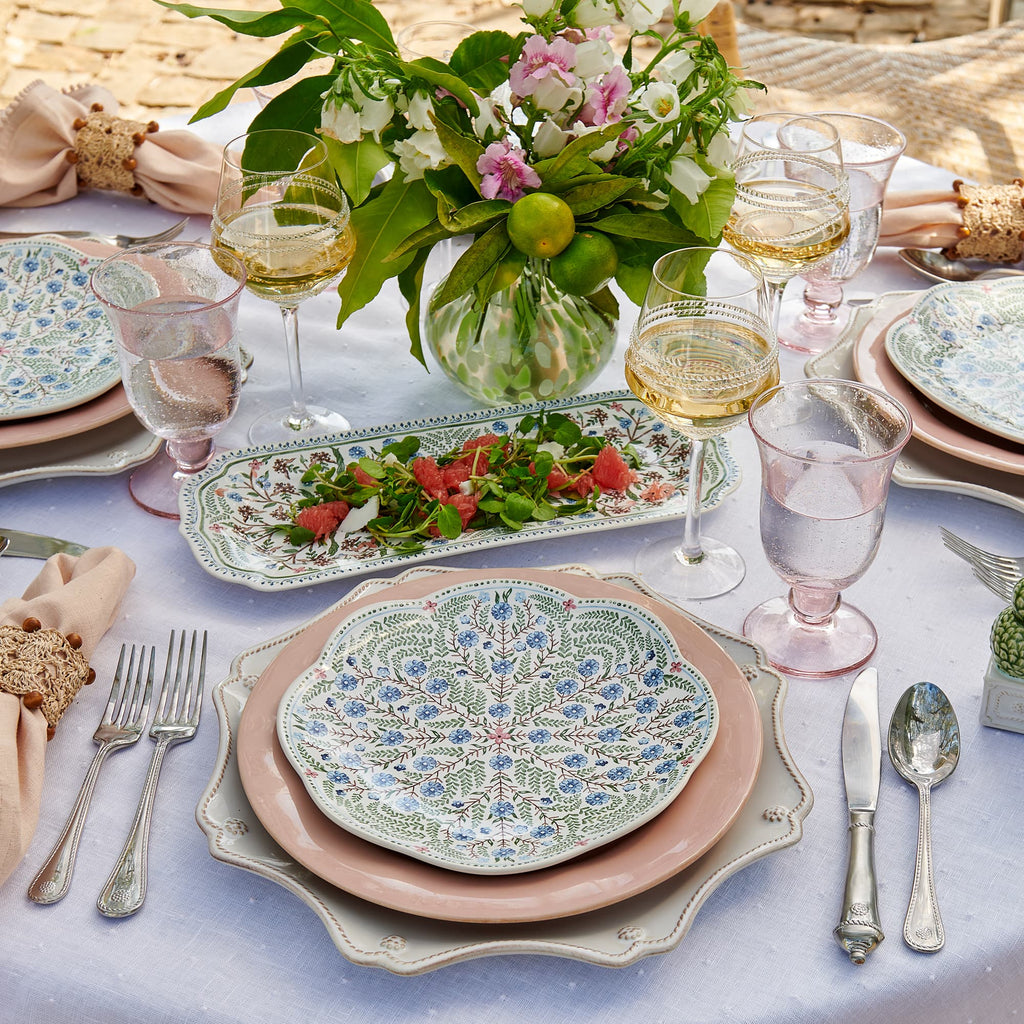 Juliska table setting with floral plates, glasses, and silverware on a white tablecloth