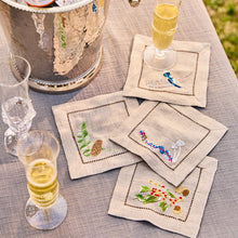 Embroidered napkins with festive designs on a table with champagne glasses.