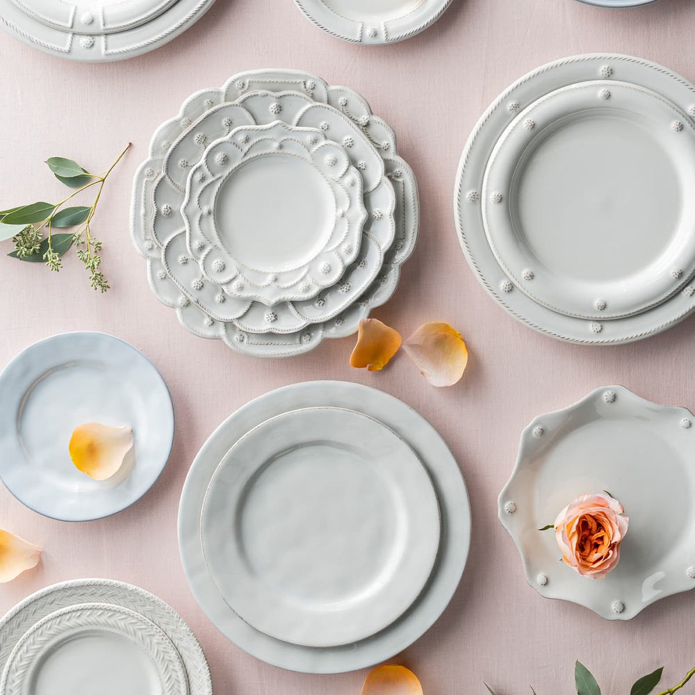 Little white plates on top of a light pink tablecloth.