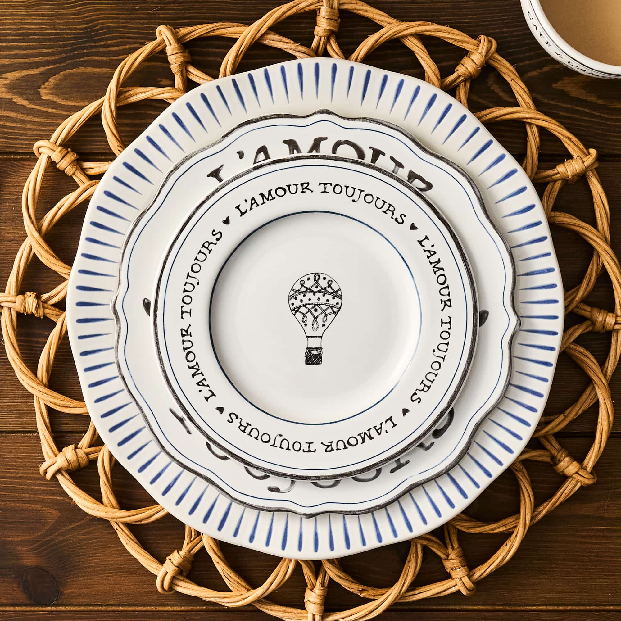 Decorative plate with 'L'Amour Toujours' text and hot air balloon design on a woven placemat.