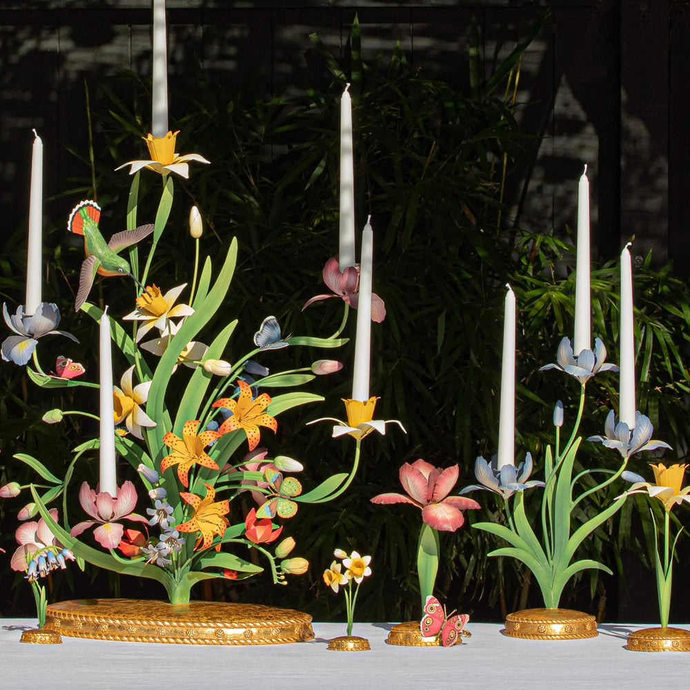 Decorative floral and candle holder with colorful flowers and white candles against a dark background.