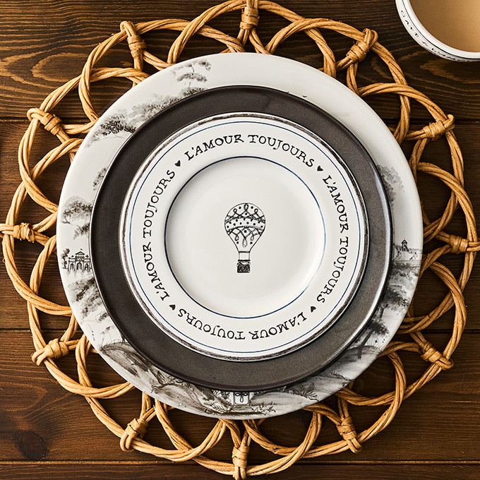 Decorative plate with 'L'Amour Toujours' text and hot air balloon design on a woven placemat.