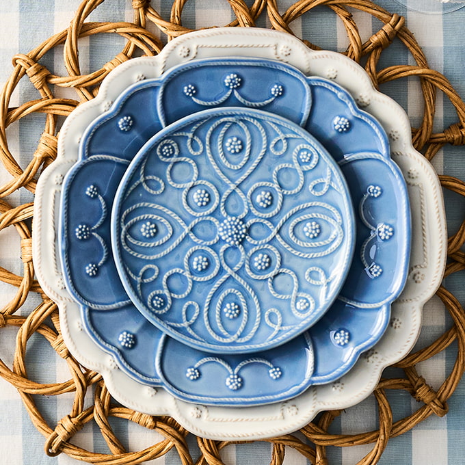 Decorative ceramic plates with intricate patterns on a woven mat.
