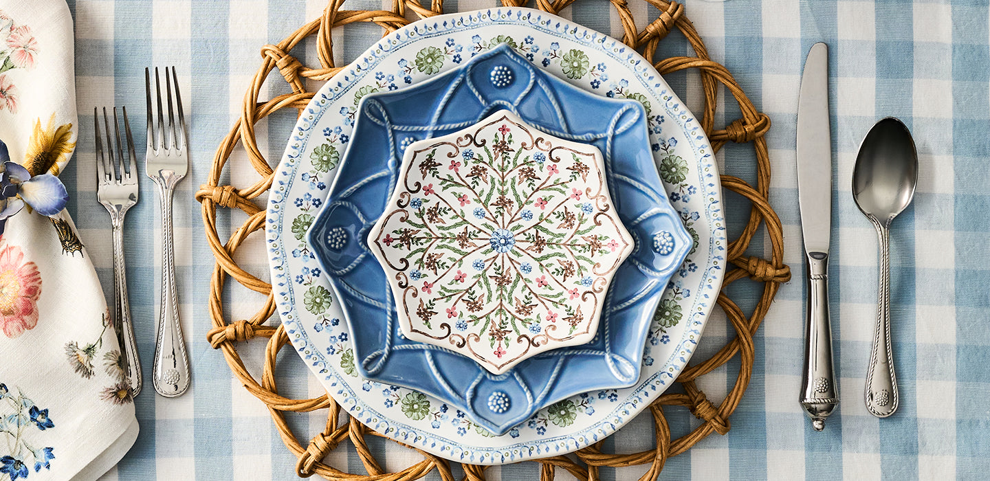 Decorative table setting with a blue and white plate, napkin, and cutlery on a checkered tablecloth.