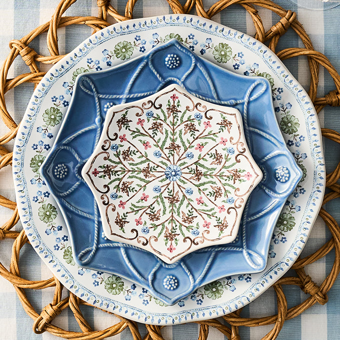 Decorative ceramic plate with intricate floral design on a woven mat