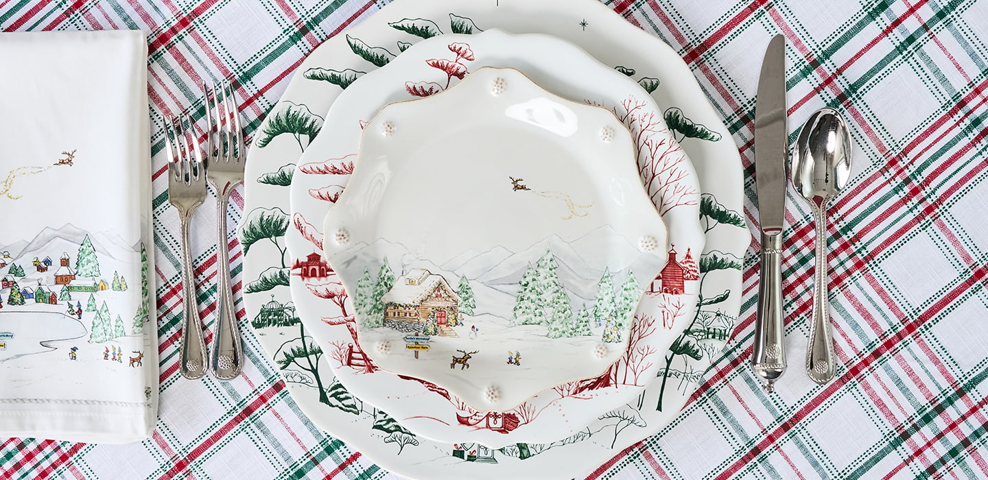 Christmas-themed place setting with a decorative plate on a plaid tablecloth.