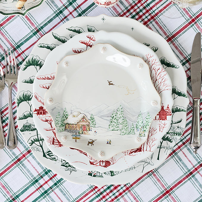Decorative Christmas-themed plate on a plaid tablecloth with cutlery.