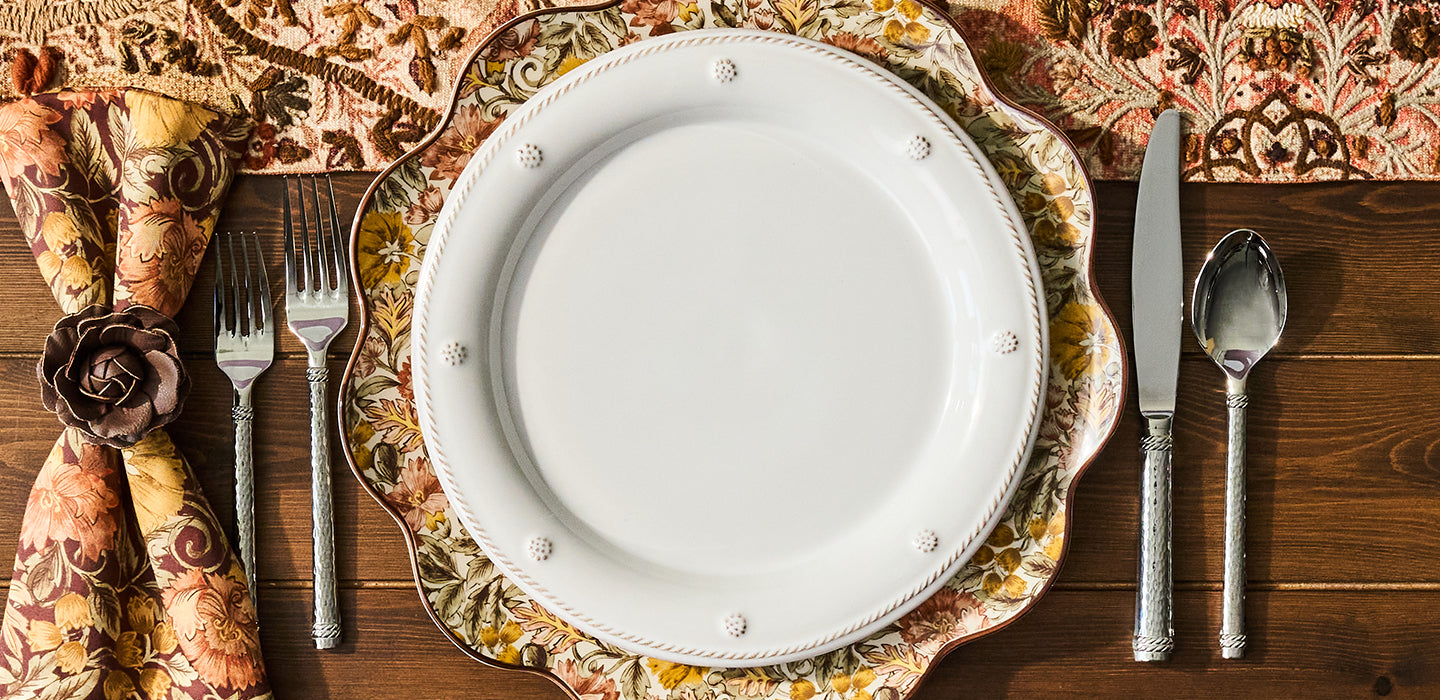 Autumnal plate with a white plate stack on top. Floral tablerunner and napkins are featured in the place setting