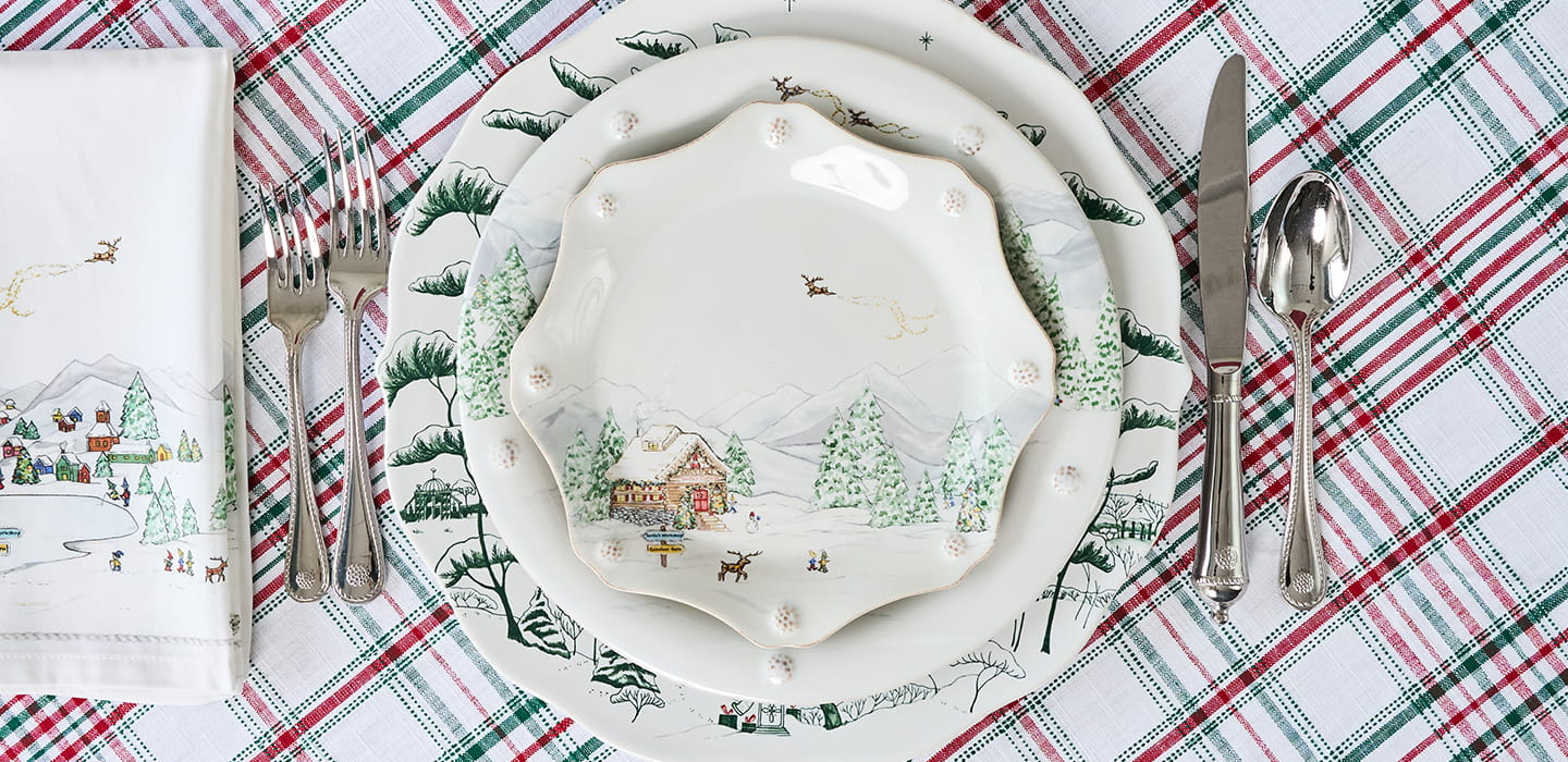 Christmas-themed place setting with a decorative plate on a plaid tablecloth.