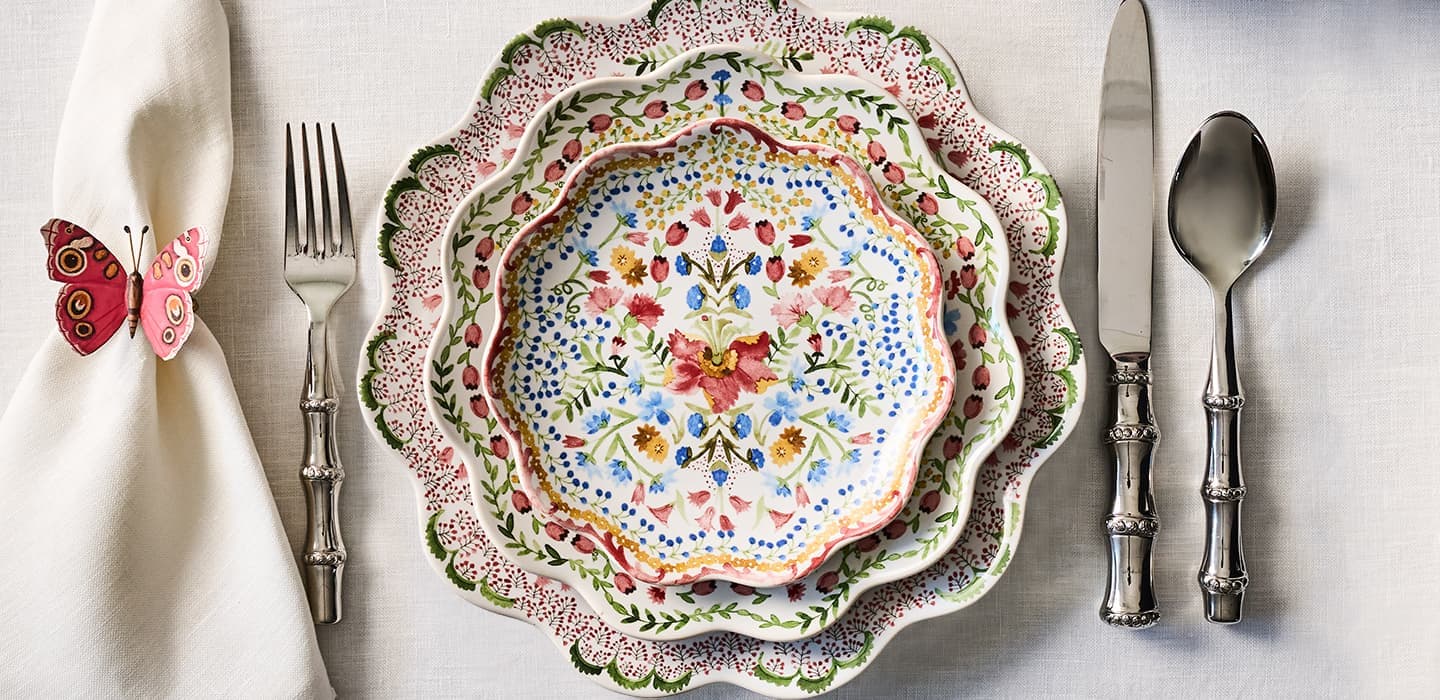 Decorative plate with floral pattern on a table setting with cutlery and a napkin.