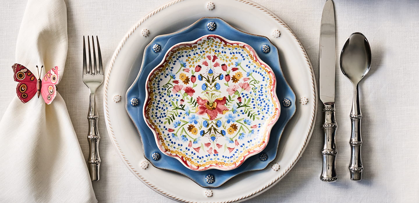 Decorative plate with floral design on a table setting with silverware and a napkin.