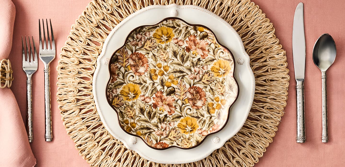 Decorative plate with floral patterns on a textured plate with cutlery and napkins.
