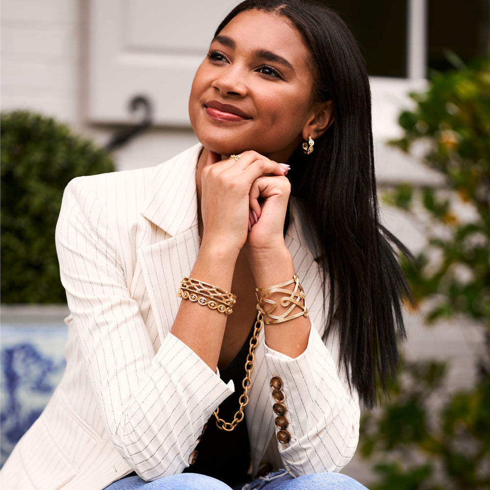Woman resting her chin on her hands while wearing gold jewelry