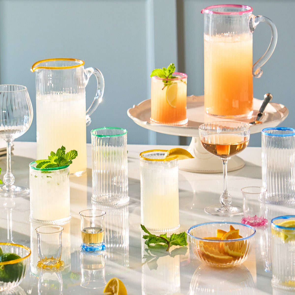 Different Nell glassware products filled with cocktails displayed on a table